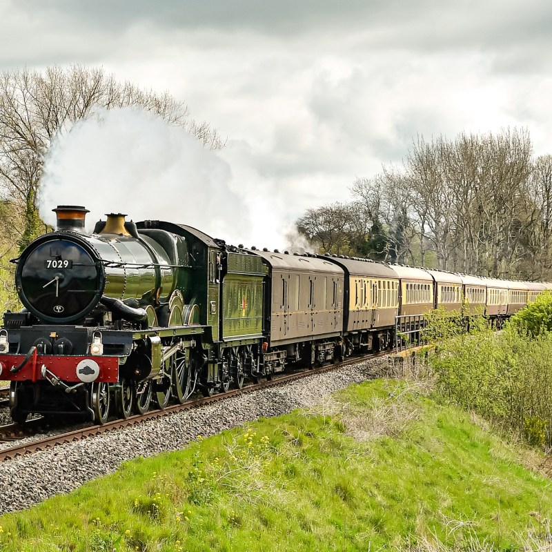 a steam engine train traveling down train tracks near a forest