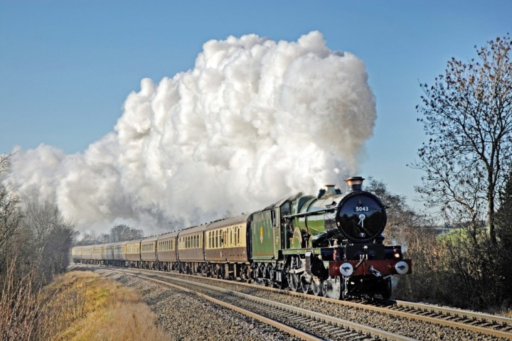 a large long train on a track with smoke coming out of it