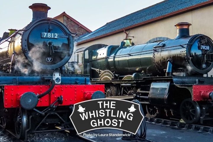 Two vintage steam locomotives at a train station labeled 'The Whistling Ghost.'