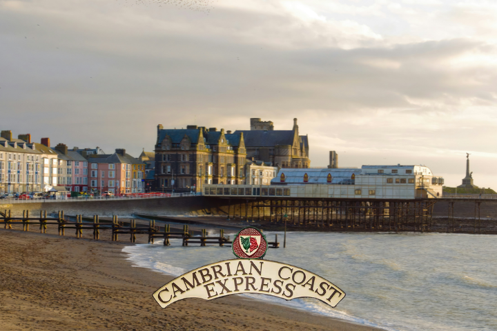 Coastal town with pier, beach, and historic building under cloudy sky.