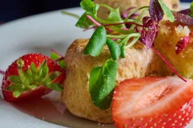 Plate of scones with strawberries and mixed greens garnish.