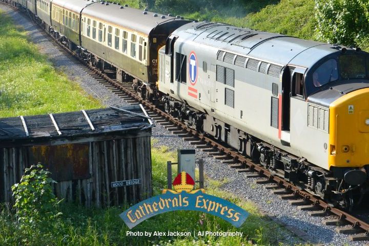 A vintage train traveling through a lush green landscape on a sunny day.
