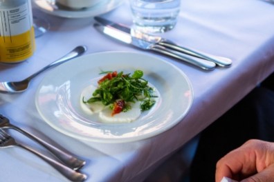 Elegant table setting with a salad plate, cutlery, and drink on a white tablecloth.