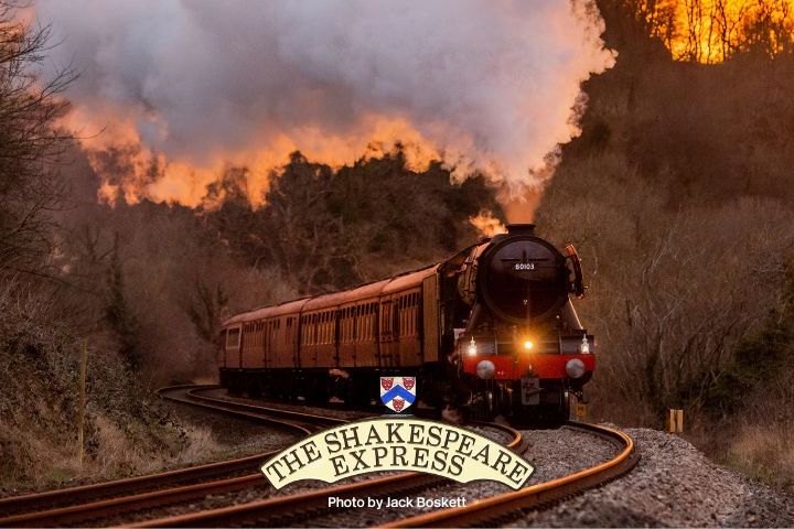 Steam train on curved track with sunset and smoke in the background.