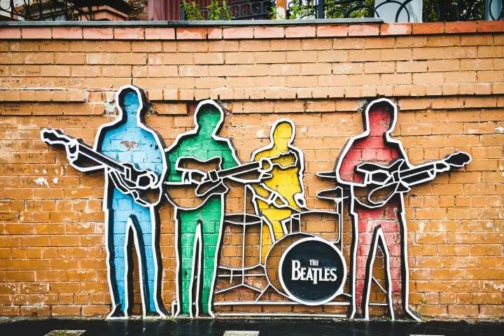 Colorful Beatles band mural on brick wall with guitars and drum.