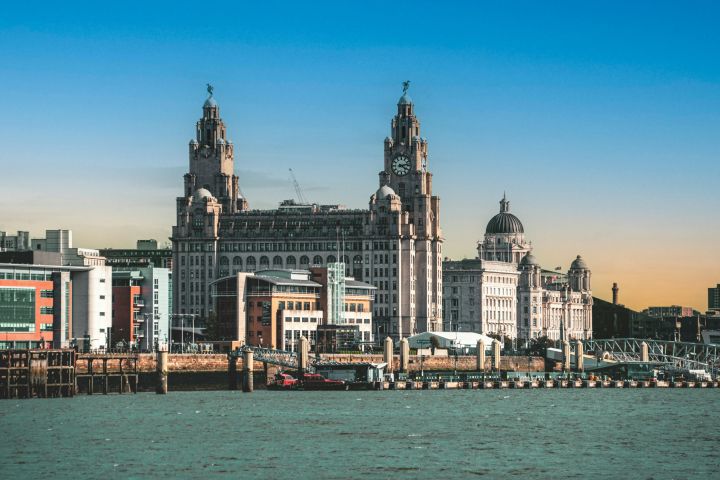 Waterfront view of historic buildings under a blue sky at sunset.